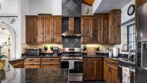 Eine moderne Küche mit Holzschränken, Edelstahlgeräten und einer Arbeitsplatte aus Granit.