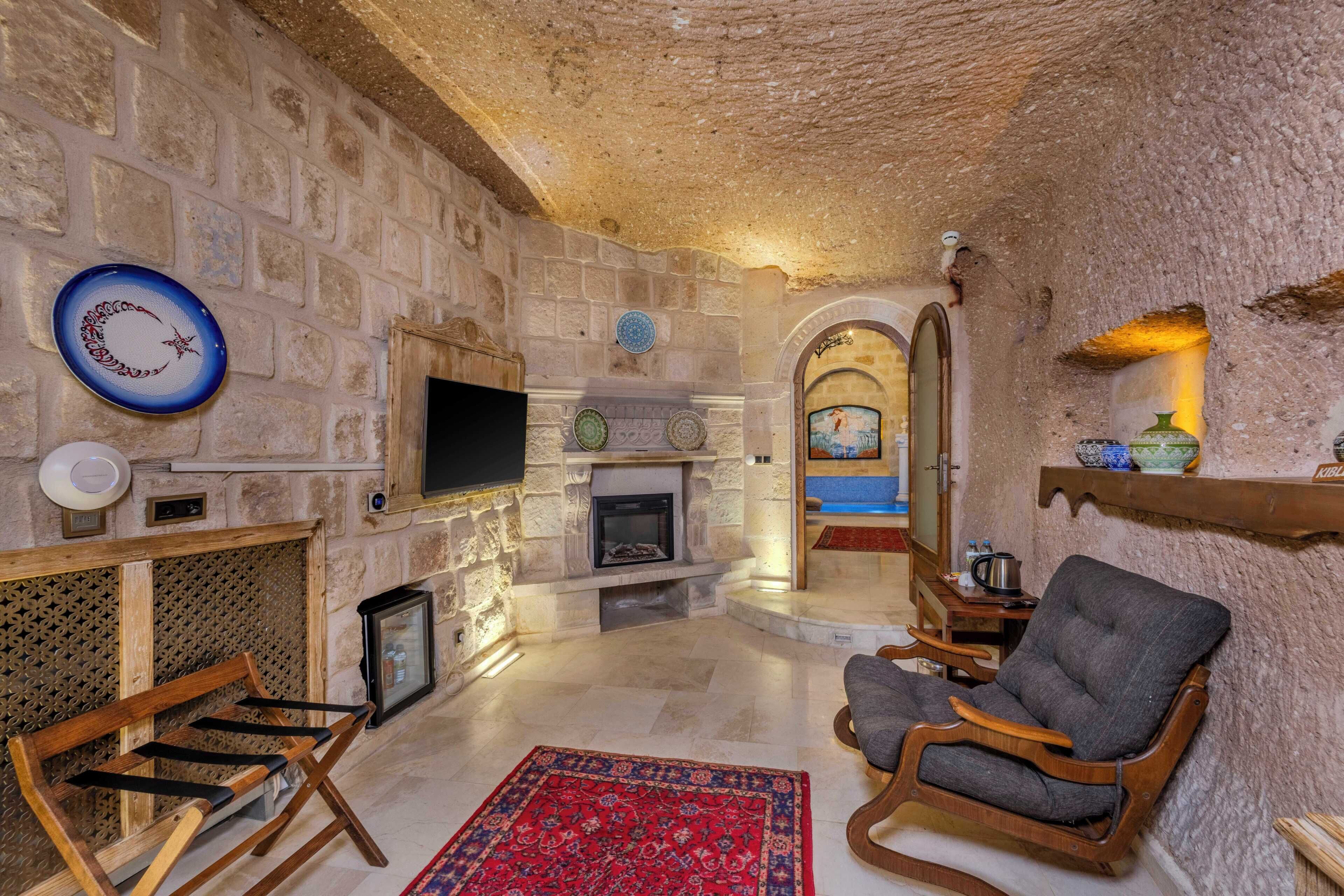 A stone-walled room with a fireplace, a television, and a wooden bench.