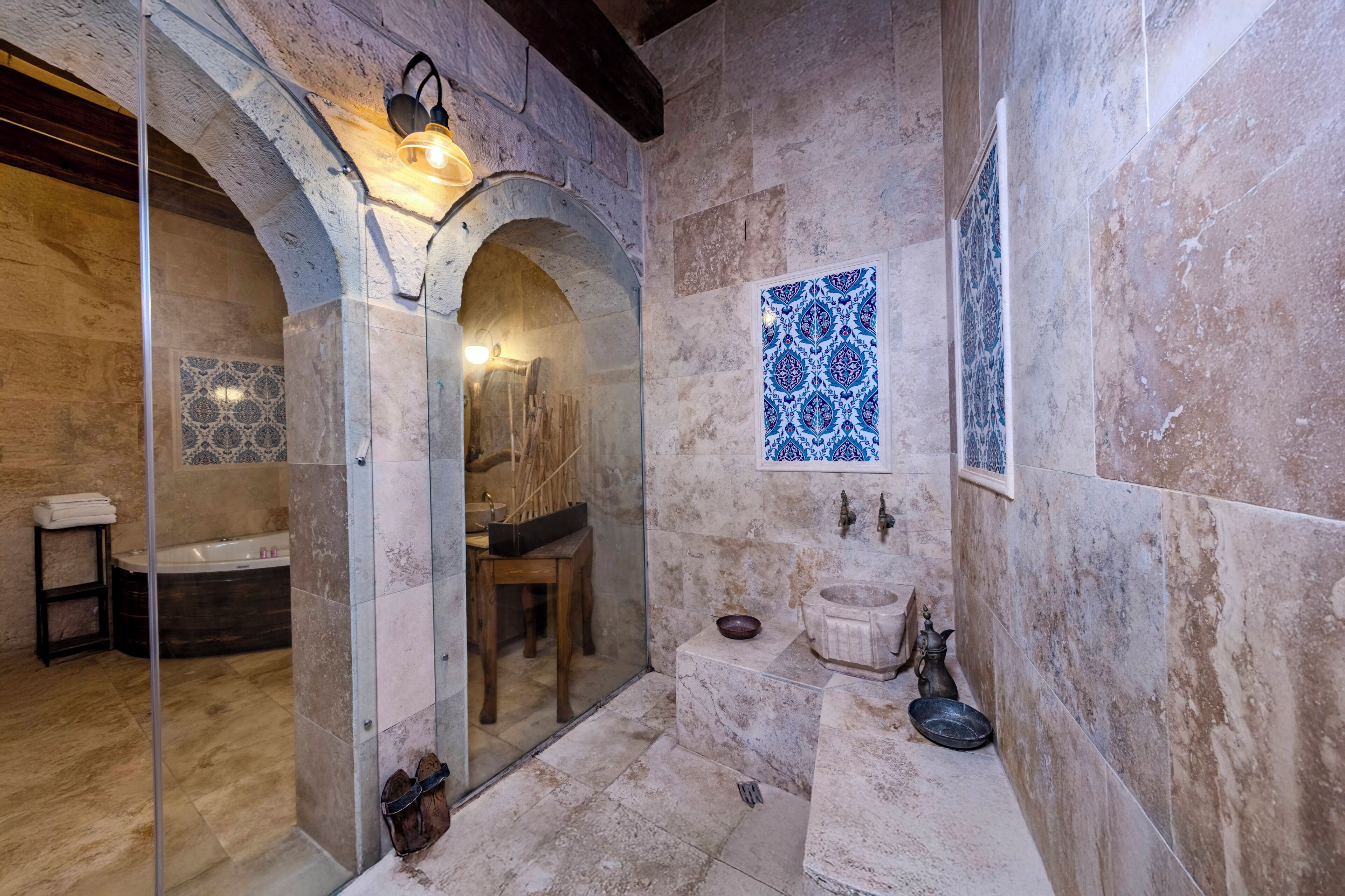 A bathroom with a bathtub, a glass-enclosed shower, a sink, and a decorative tile pattern.