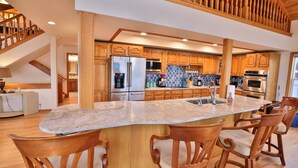 A spacious kitchen with wooden cabinets, a large island with bar stools, and a built-in oven. - Experience Spacious Coastal Living at Seascape - Stunning Views of Heceta Beach  (Florence)