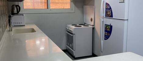 A compact kitchen with a built-in oven, a microwave, and a refrigerator.