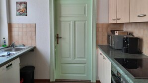 A compact kitchen with a green door, a sink, a coffee maker, and a stove.