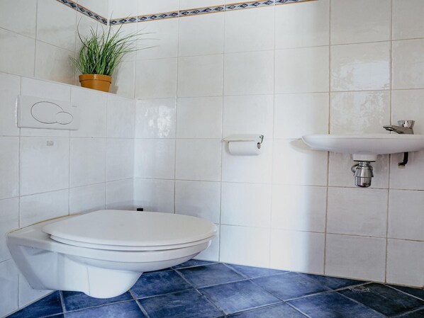 Une salle de bain avec des toilettes, un lavabo et une plante en pot.