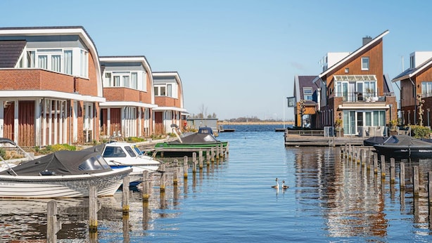 A canal with houses on either side, boats docked, and a clear sky. - Uitgeest Apartment with Waterpark Nearby (Uitgeest)