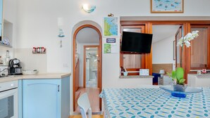 Una cocina con cafetera, un lavabo y un comedor con mesa y sillas.