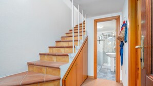 Una escalera con escalones de madera y barandillas blancas que lleva a un baño.