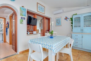 A dining area with a table and chairs, a television, a cabinet with glass doors, and a 'No Smoking' sign.