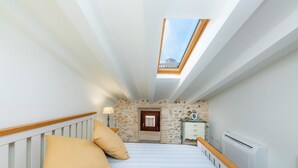Ein Schlafzimmer mit Oberlicht, einem Bett mit Kissen, einem Schminktisch und einer Heizung.