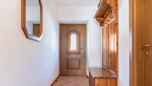 A hallway with a wooden door, a mirror, and a wooden bench.