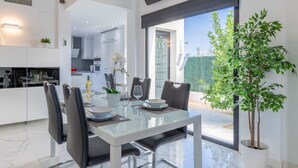 A modern dining area with a glass table, black chairs, and a potted plant.