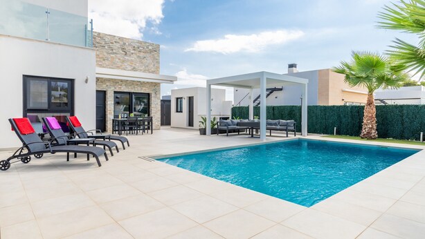 A modern outdoor pool area with lounge chairs and a covered seating area.