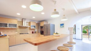 A modern kitchen with a central island, bar stools, built-in appliances, and pendant lighting. - Country House 'Villa Papa' with Mountain View, Wi-Fi and Air Conditioning (Pollenca)