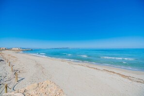 A beach with a clear sky, calm sea, and a sandy shore. - Villa 'Son Serra' with Garden and Wi-Fi (Son Serra de Marina)