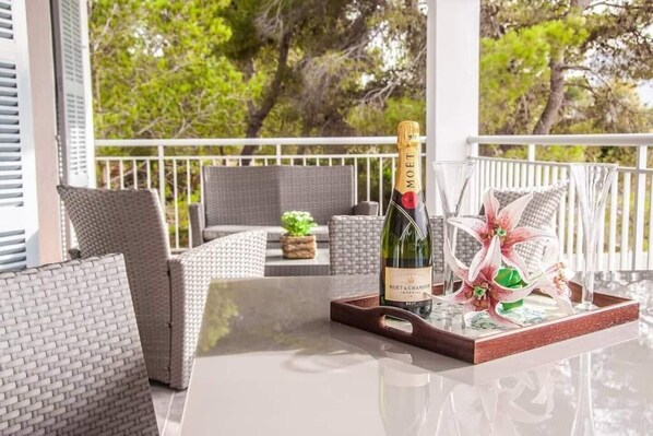 A balcony with wicker furniture, a bottle of Moët & Chandon champagne, and a decorative arrangement.