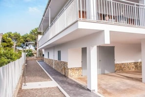 A building with a covered outdoor area, stone wall, and a gated entrance.