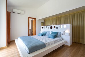A modern bedroom with a bed, bedside table, and an air conditioning unit.
