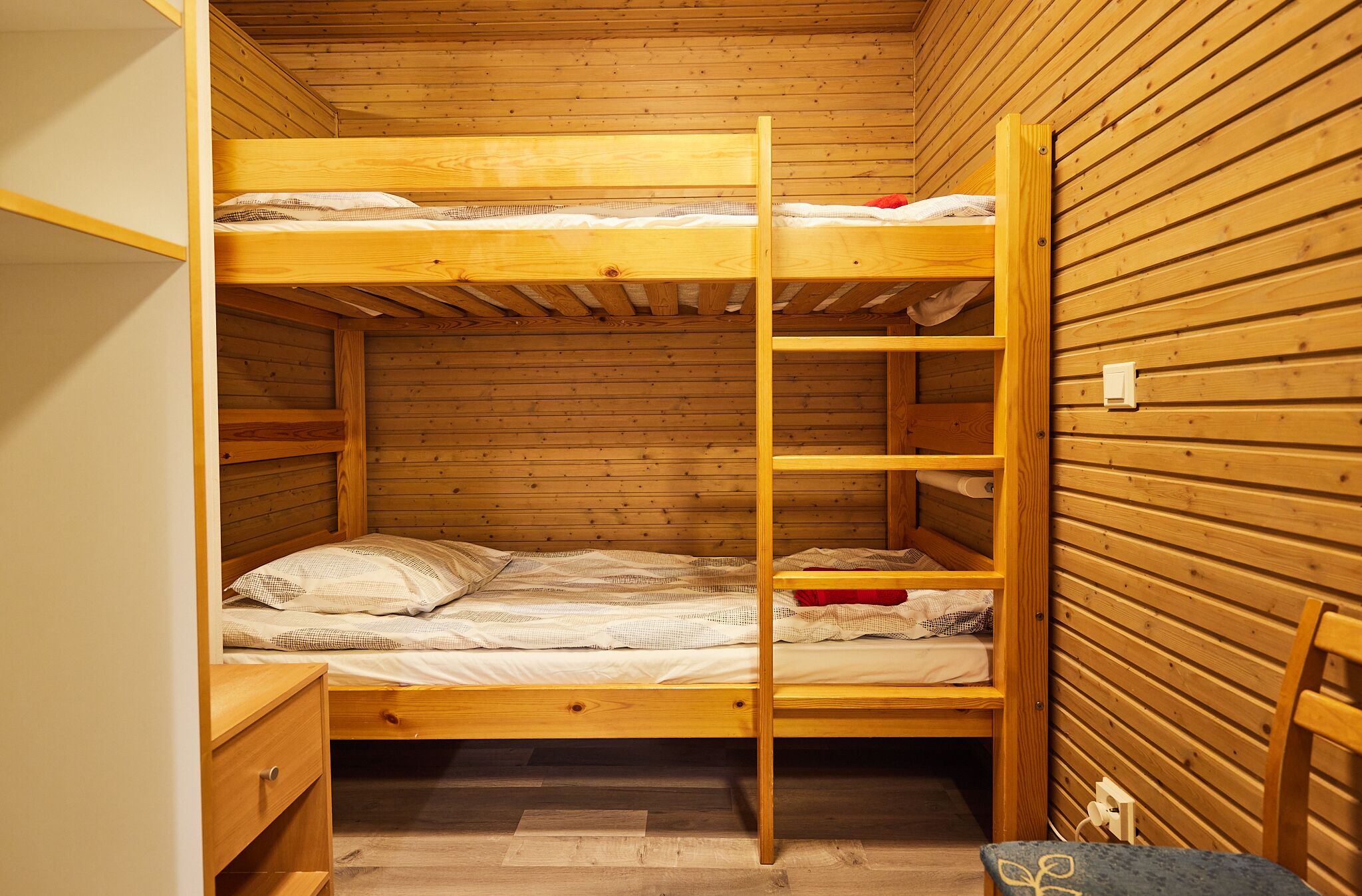 A bunk bed room with wooden walls and a wooden floor.