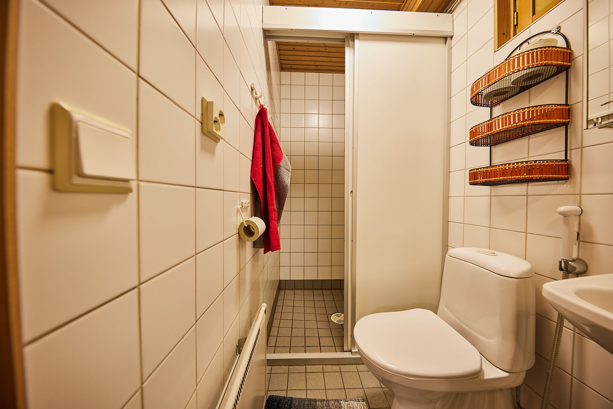 A small bathroom with a toilet, a shower stall, and a sink.