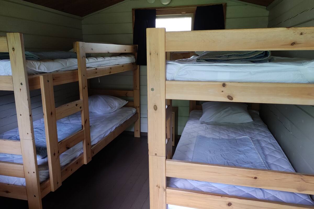Una cabaña con tres literas de madera, cada una con ropa de cama blanca.