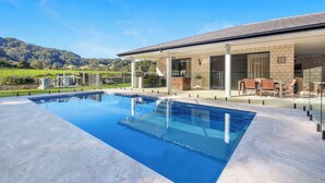 A modern house with a swimming pool, outdoor seating, and a view of the mountains. - Casa Bella - Luxury 3 Bedroom Rural Retreat (Coffs Harbour)