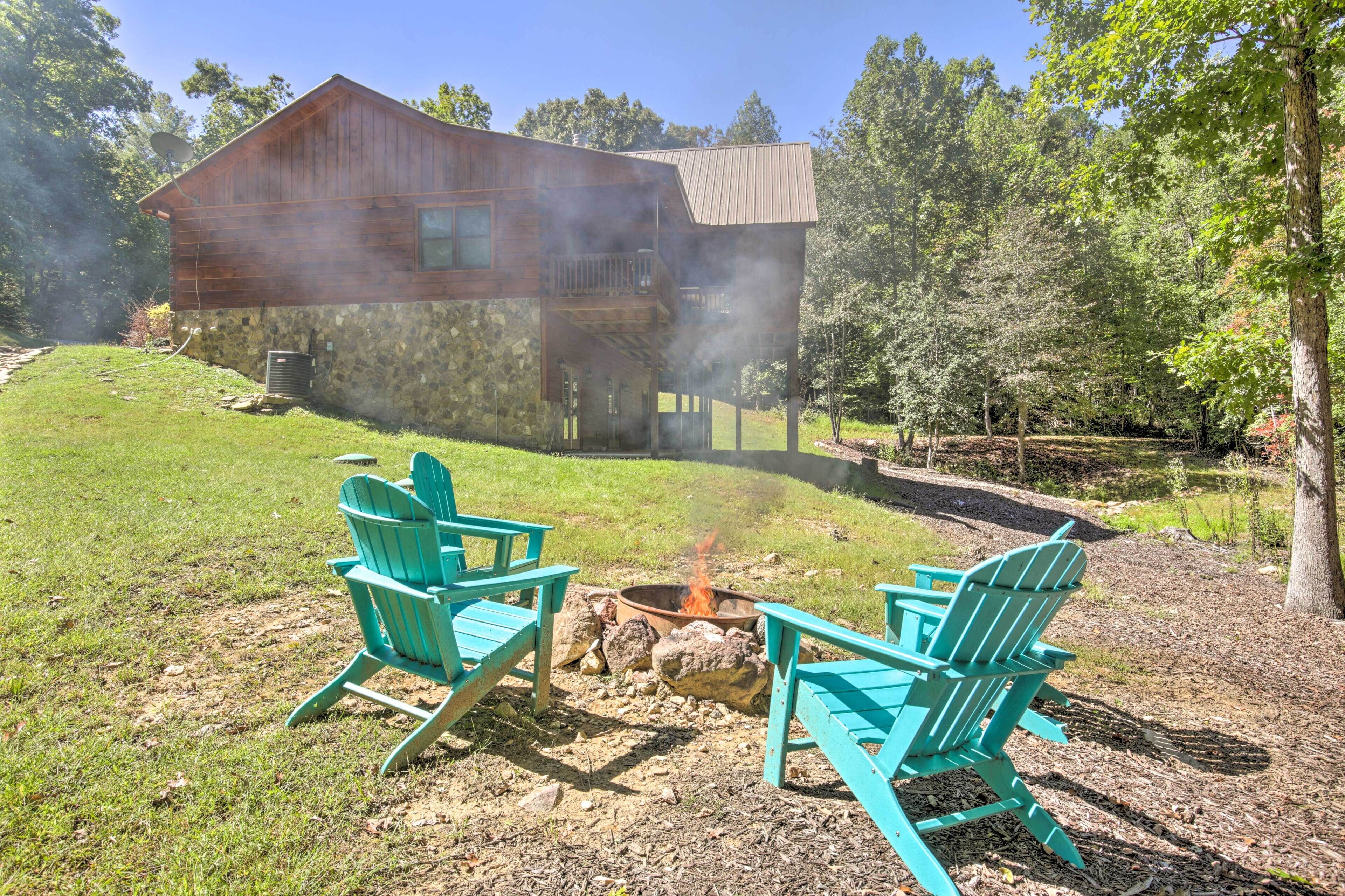 A rustic cabin with a stone foundation and wooden exterior, surrounded by a grassy yard and trees.