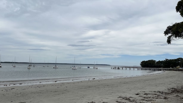 A beach with a pier extending into calm waters.