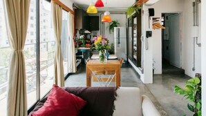 Eine moderne Wohnung mit Essbereich, einer Couch und einem großen Fenster mit Vorhängen.