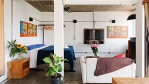 Ein Zimmer mit einem Bett, einer Couch, einem Fernseher und Bildern an den Wänden.