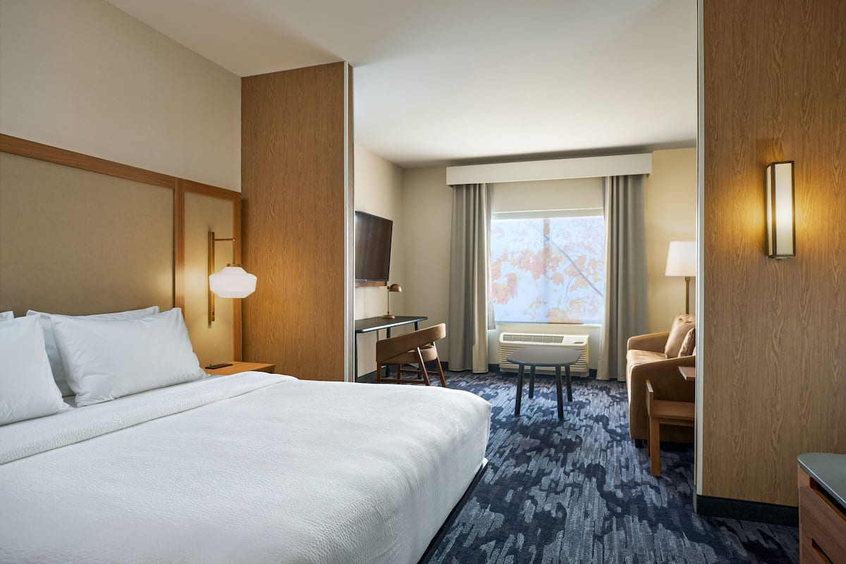 Een hotelkamer met een groot bed, een bureau, een stoel, een televisie en een raam met gordijnen.