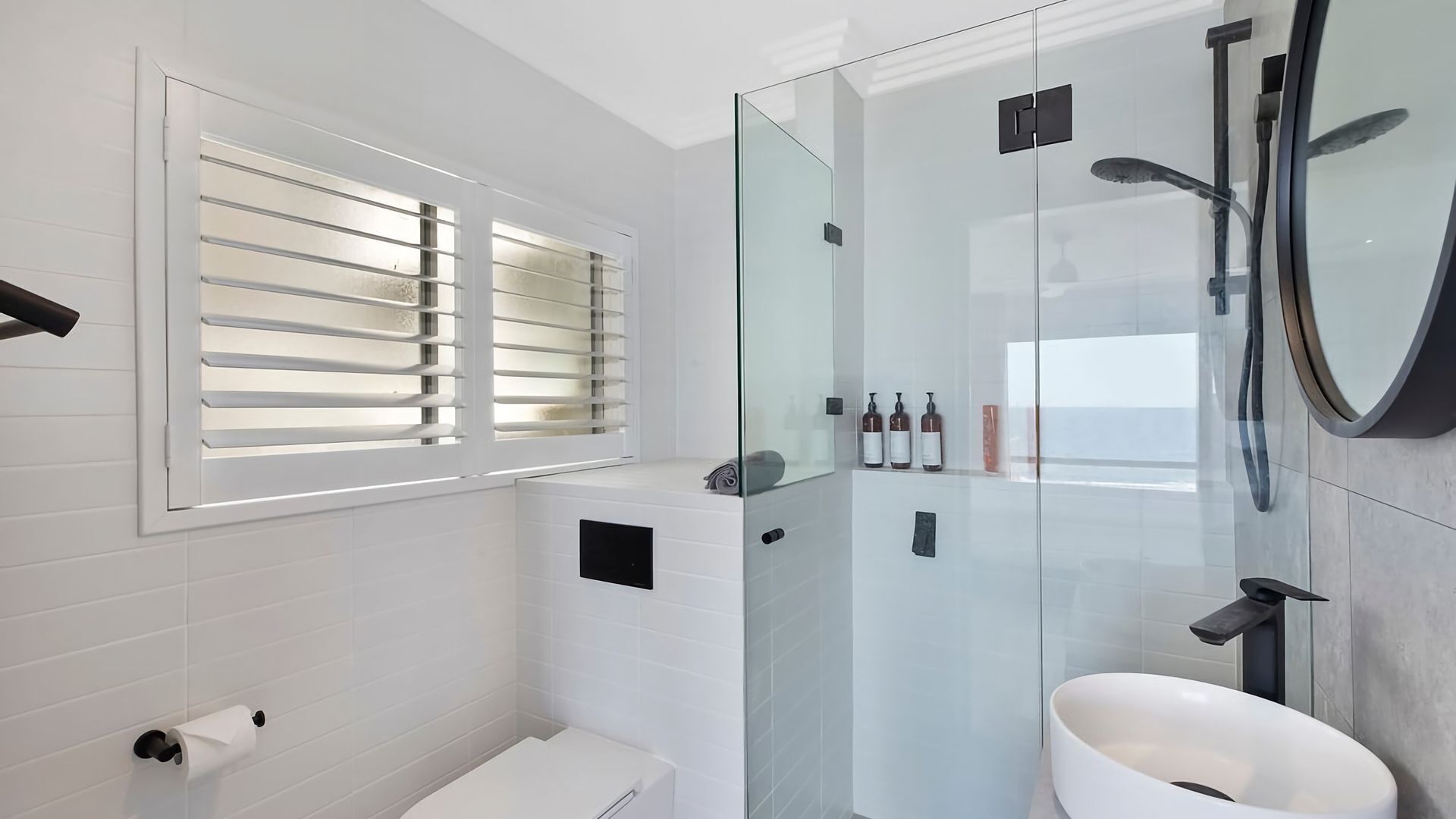 A modern bathroom with a glass-enclosed shower, a toilet, and a sink.