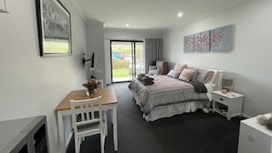A bedroom with a bed, bedside table, chair, and a desk with a vase of flowers. - River Gardens Axedale Pet friendly B & B Farm stay - Motel Room (Axedale)