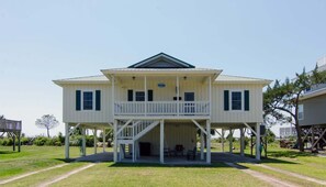 A two-story house with a balcony, a porch, and a staircase leading to the upper floor. - Sound Choice:Oceanfront Home;Sunset Views/Dolphin Sightings on St. Helena Sound; Screened Porch (Edisto Beach)