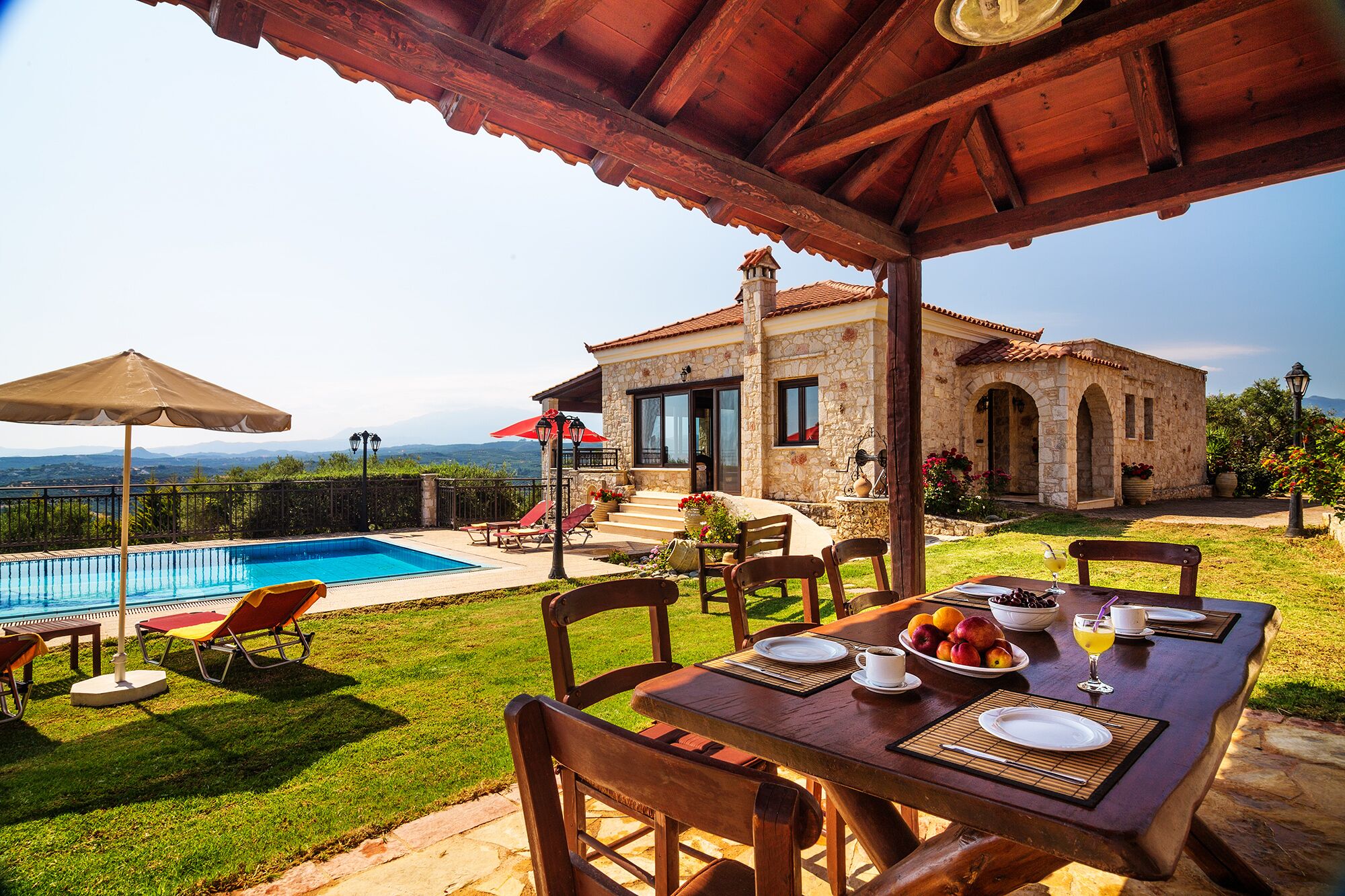 Une villa en pierre dotée d’une piscine, d’un espace repas extérieur et offrant une vue sur les montagnes.
