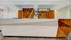 A reception desk with a clock, a sign indicating 'RECEPTION', and an air conditioning unit above it. - Treebo A5 (Indore)