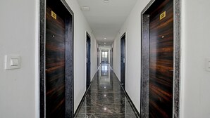 A long, narrow hallway with dark wooden doors on both sides, numbered 307 and 306. - Treebo A5 (Indore)