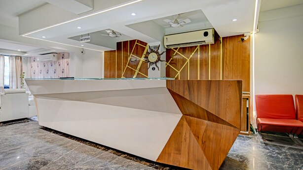 A reception desk with a modern design, including a clock and an air conditioning unit above it. - Treebo A5 (Indore)