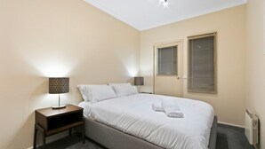 A neatly made bed with white linens, two bedside lamps with patterned shades, and a window with blinds. - Prosecco - Dinner Plain (Dinner Plain)