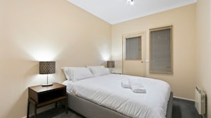 Relax in a serene space with a large bed, bedside tables, and windows with blinds.