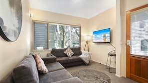 Relax in this stylish living room with a large window, flat-screen TV, and comfortable sofa.