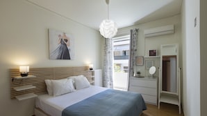 A bedroom with a bed, bedside tables, a nightstand, a hanging light fixture, a window with curtains, and a door with a mirror. - MisaraliotouA3 · 3BR Prime APT a breath away from (Athens)