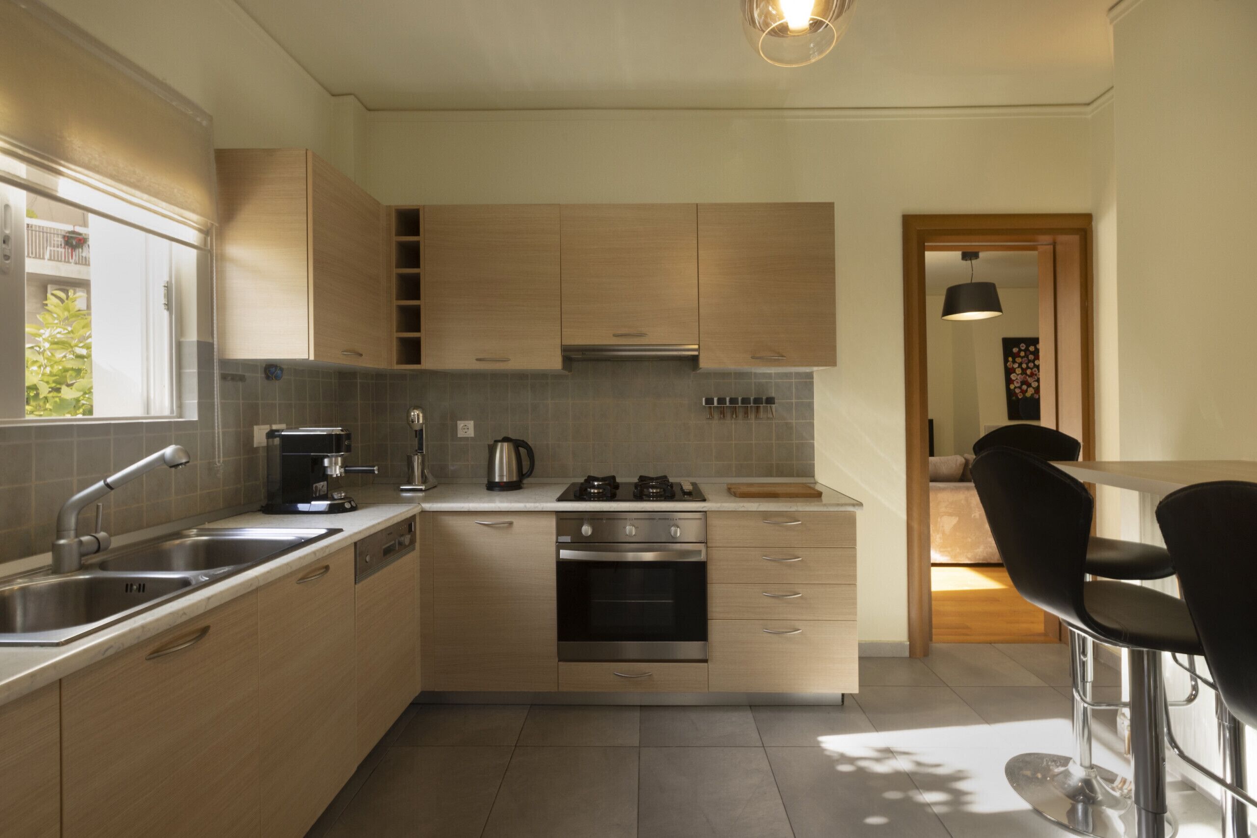 A modern kitchen with stainless steel appliances, wooden cabinets, and a bar area with black bar stools.