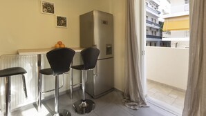 A compact kitchen with a refrigerator, two bar stools, and a small table. - MisaraliotouA3 · 3BR Prime APT a breath away from (Athens)