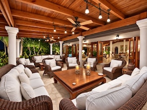 A spacious outdoor lounge area with wicker furniture, a wooden coffee table, and ceiling fans. - Villa Casa Nostra by KlabHouse 5BDRM w/Pool and Chef (La Romana)