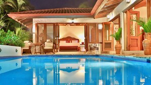 Ein Schlafzimmer am Pool mit Bett, Sessel und Tisch.