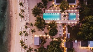 Eine Vogelperspektive eines Resorts mit großem Pool, mehreren Liegebereichen und einer Lage direkt am Strand.