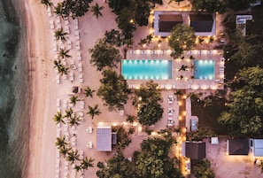 An aerial view of a resort with a beach, two swimming pools, and numerous sun loungers. - Villa Casa Nostra by KlabHouse 5BDRM w/Pool and Chef (La Romana)