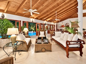 A spacious lobby with high ceilings, wooden beams, wicker furniture, and a pool area visible through glass doors. - Villa Casa Nostra by KlabHouse 5BDRM w/Pool and Chef (La Romana)
