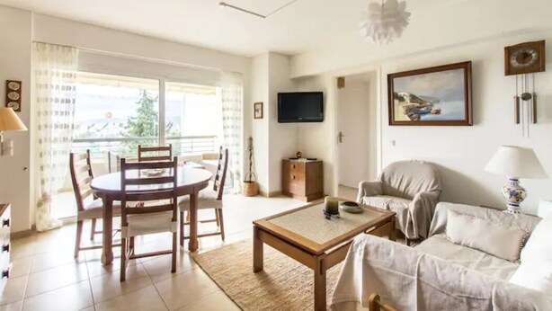 A living room with a dining table, sofa, and TV. - Compact 3 room apartment in Mall Athens. (Marousi)