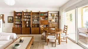 A modern living room with a large bookshelf, a dining table with chairs, and a sofa. - Compact 3 room apartment in Mall Athens. (Marousi)