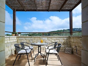 Relax on the terrace with a clear view of the surrounding landscape, featuring a pergola and comfortable seating for two.